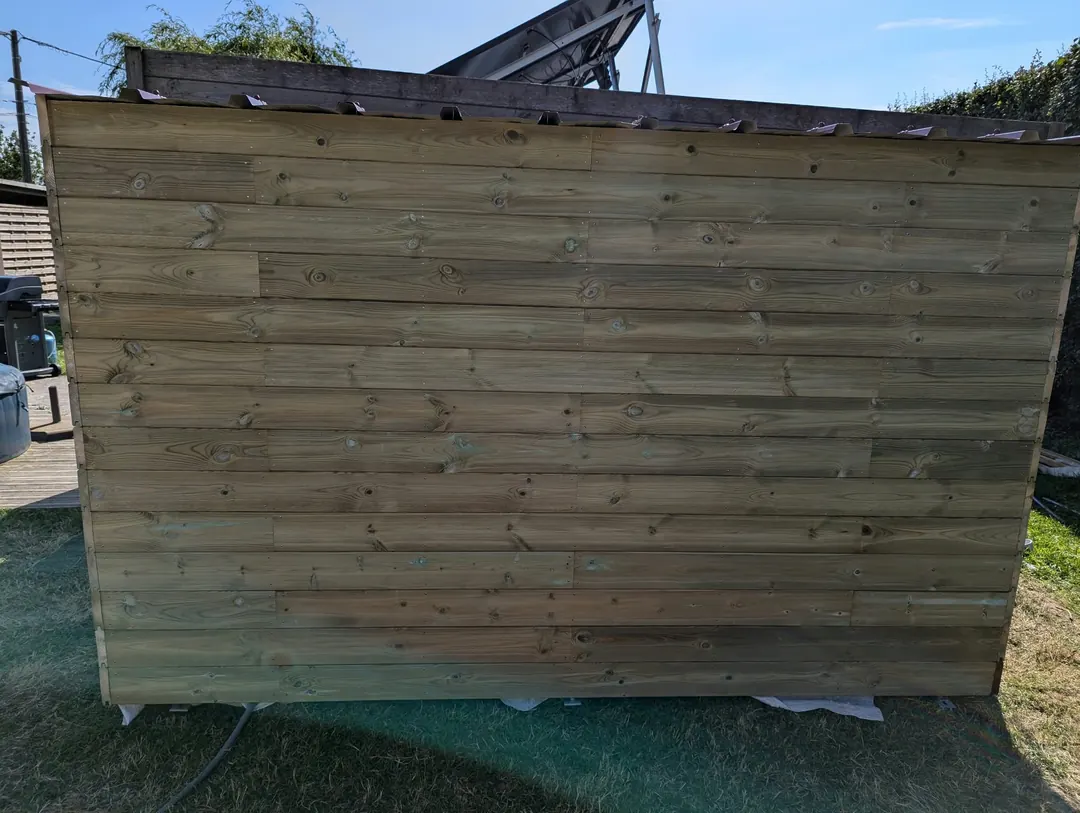 Mur en bardage bois horizontal d'un abri de jardin, pelouse devant.