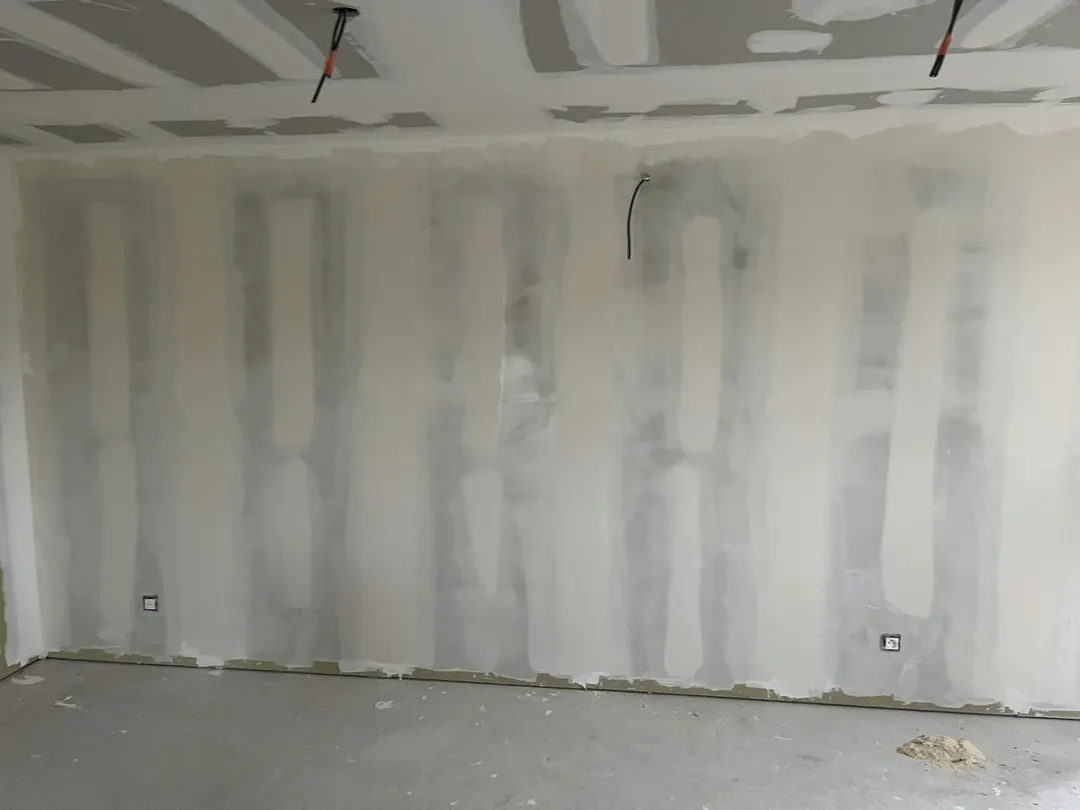 Grand mur en plaques de plâtre aux joints enduits et poncés, sol en béton.