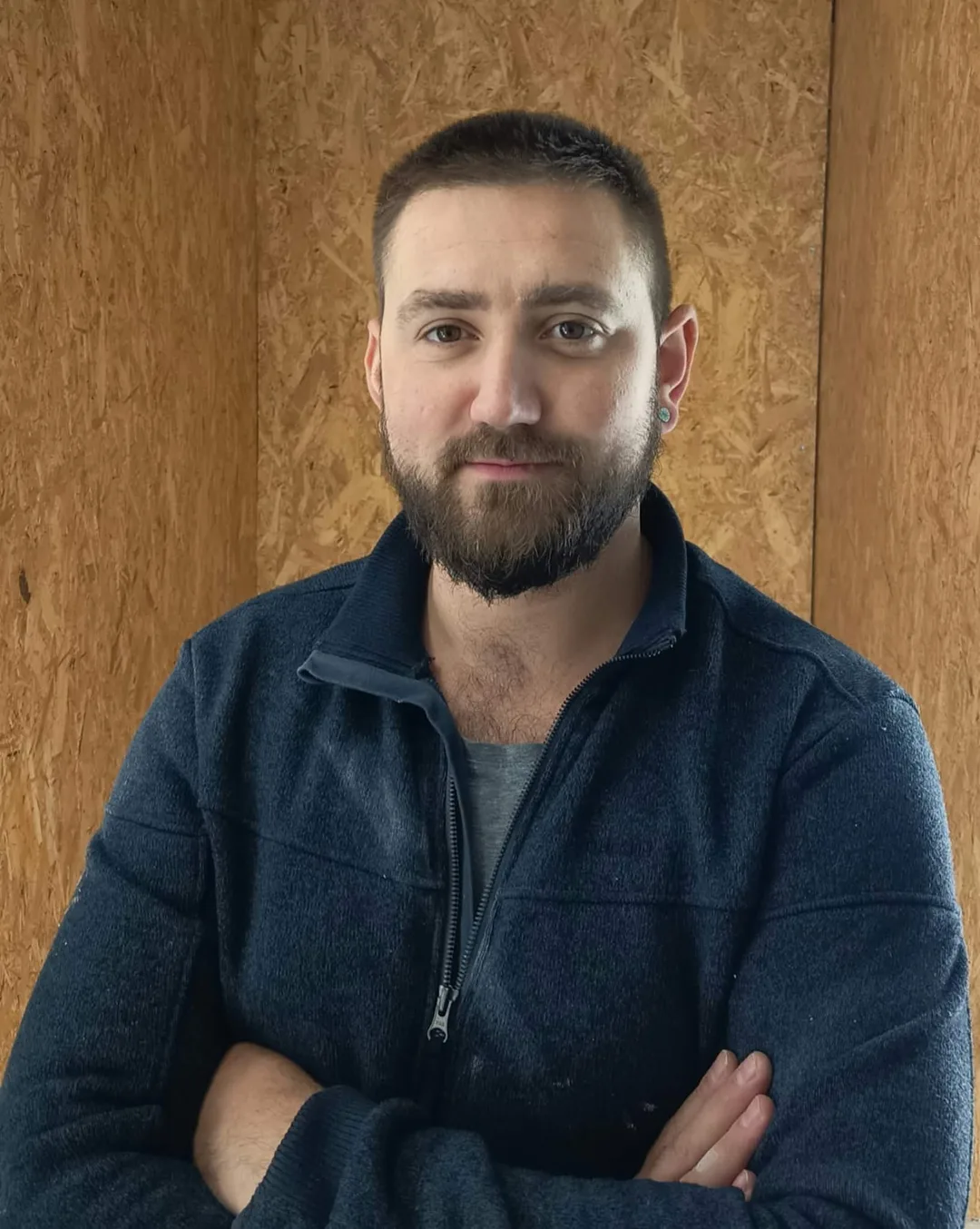 Gaëtan Caffier, gérant de CGR Habitat, bras croisés devant un mur en panneaux OSB